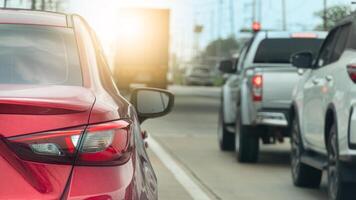 Rear side of red car with turn on brake light. Many car stop by traffic red light condition. Truck car passthrough on front. background of many pole under clear sky. photo