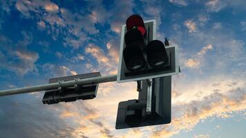 Traffic light hangs on a pole indicating a red signal to stop. On the back side are two signal indicators. under view of evening sky. photo