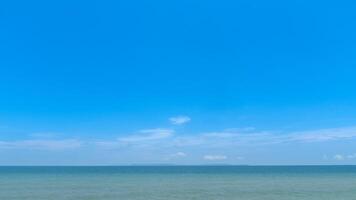 Landscape nature background of bright blue sky with a few wispy clouds over a calm light turquoise sea. Horizon line is distinct suggesting a peaceful day. photo