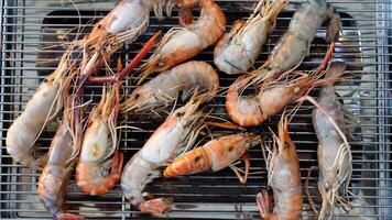 Grilling activity on a steel grid. Cooked shrimp that still has orange color. Above view of grilled shrimps are arranged on a steel grid. photo