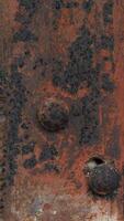 Textured surface with rust and discoloration. Surface appears to be metal with rivets or bumps and Nut head. Indicating wear and age. Focus is on the texture and the effects of corrosion. photo