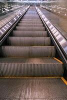 The escalator is empty and has a yellow stripe photo