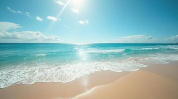 Tropical beach with turquoise ocean waves, golden sand, blue sky and sun rays reflecting on water on a sunny day photo