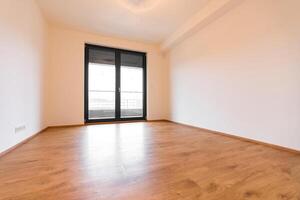 Modern empty room exuding simplicity, with wooden floors and a tilt and turn window system. photo