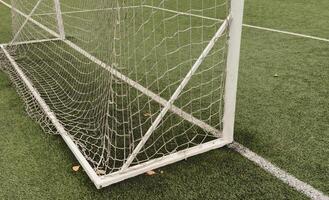 Soccer goal net backstop on a green turf field. Straight on view with white netting pattern and metal posts. photo