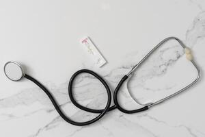 Medical layout on white background, flat lay. stethoscope or phonendoscope surrounded by vials, ampoules and test tubes. photo