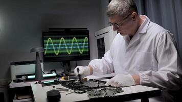 Electronics Engineer Repairing a Laptop. The background includes various electronic tools and a monitor displaying a waveform, suggesting diagnostics and troubleshooting video