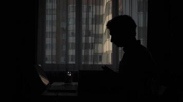 Programmer working from home in dark room with laptop video