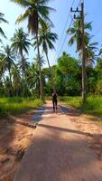 FPV drone shot of woman jogging on tropical path with palm trees on sunny day video