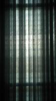 Dark sheer curtain folds backlit by bright window light photo