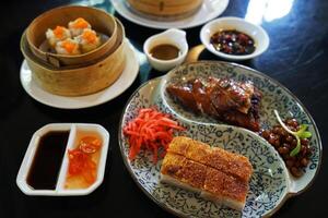 Close up crispy barbecue pork served with roasted honey duck and Shumai photo