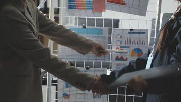Two people shaking hands in front of a wall with graphs video