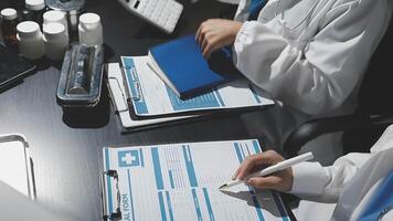 Two doctors working at a desk with papers and pens video