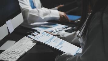 A doctor is working on a computer while another person is sitting at a desk video