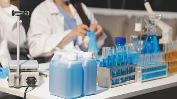 Two people in lab coats working on a table with bottles and other items video