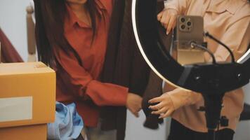 Two women are looking at a camera while standing in front of a mirror video