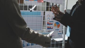 Two business people talking in front of a wall with graphs video