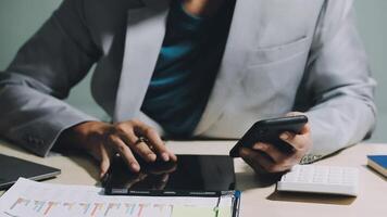 A man in a suit is using his phone and tablet video