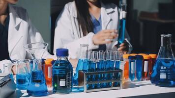 Two women in lab coats are working on a table with blue and white liquids video