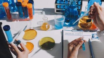 A person is holding a test tube and writing on a notebook video