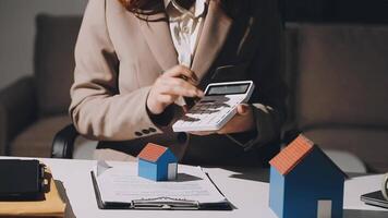 A woman in a business suit is using a calculator to calculate the value of her home video