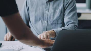 A man is holding a laptop while another person is sitting at a desk video
