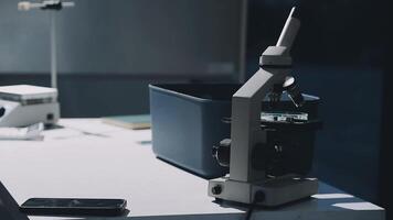 A microscope is sitting on a desk next to a cell phone video