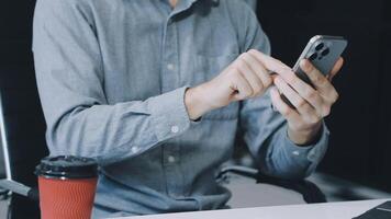 A man is using his phone while sitting at a desk video