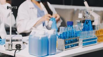 Two women in lab coats working on a table with bottles video