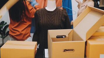 A woman is standing next to boxes and a man is standing next to a mannequin video