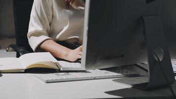 uma mulher é sentado às uma escrivaninha com uma computador e uma caderno video
