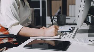 A person sitting at a desk with a pen and a computer video