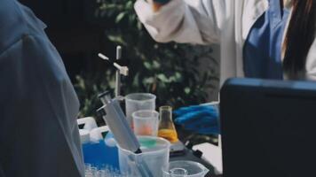 Two people in lab coats and gloves working on a computer video