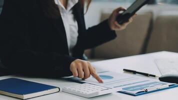 Businesswoman using calculator and tablet at desk video