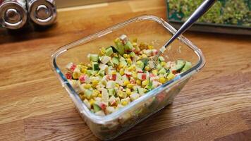 Vibrant surimi salad in a glass bowl on a rustic wooden surface, surrounded by spice containers and fresh microgreens during professional culinary preparation. Healthy and balanced diet surimi salad video
