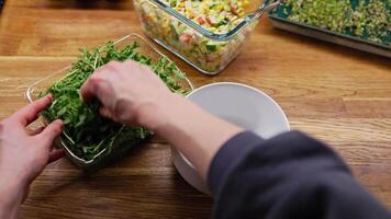 POV shot. chef adds fresh arugula to bowl of salad made with corn, cucumber, and crab sticks, mixing the ingredients together on wooden kitchen counter. Chef mixing fresh arugula with surimi salad video