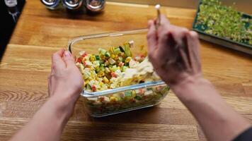 POV shot. skilled chef mixing surimi salad with mayonnaise, combining fresh ingredients in glass bowl on rustic wooden surface, creating colorful lunch preparation. Chef preparing surimi salad video
