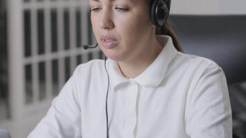 Customer service representative in headset communicating via laptop, engaged in support or virtual assistance in modern office setting. 12 video
