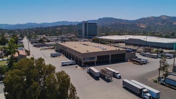 Aerial view of a commercial area with trucks and buildings against a mountainous backdrop photo