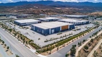 Aerial view of large industrial buildings surrounded by mountains and landscaped areas photo