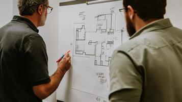 Two individuals discussing a building plan on a whiteboard photo