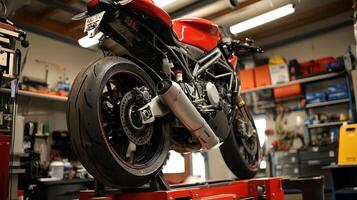 A motorcycle on a lift in a workshop, showcasing its rear tire and exhaust system photo