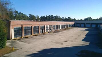 A spacious industrial building with large windows and an empty parking lot under clear skies. photo