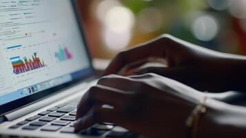 A close-up of hands typing on a laptop displaying colorful data charts and graphs photo