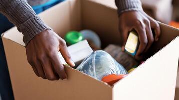 A person sorting through a box filled with various food items and containers photo