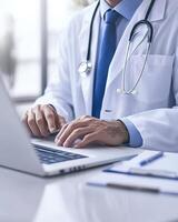 A medical professional typing on a laptop, focused on work in a clinical setting photo