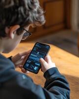 A young person using a smartphone, engaged in an app or game on a wooden table photo