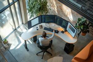 A person working at a modern desk with multiple monitors in a bright office space photo