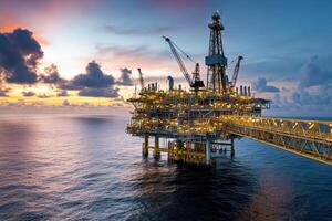 An offshore oil rig illuminated at sunset, showcasing industrial infrastructure over water. photo