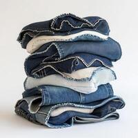 A neatly stacked pile of various denim jeans in different shades and styles. photo